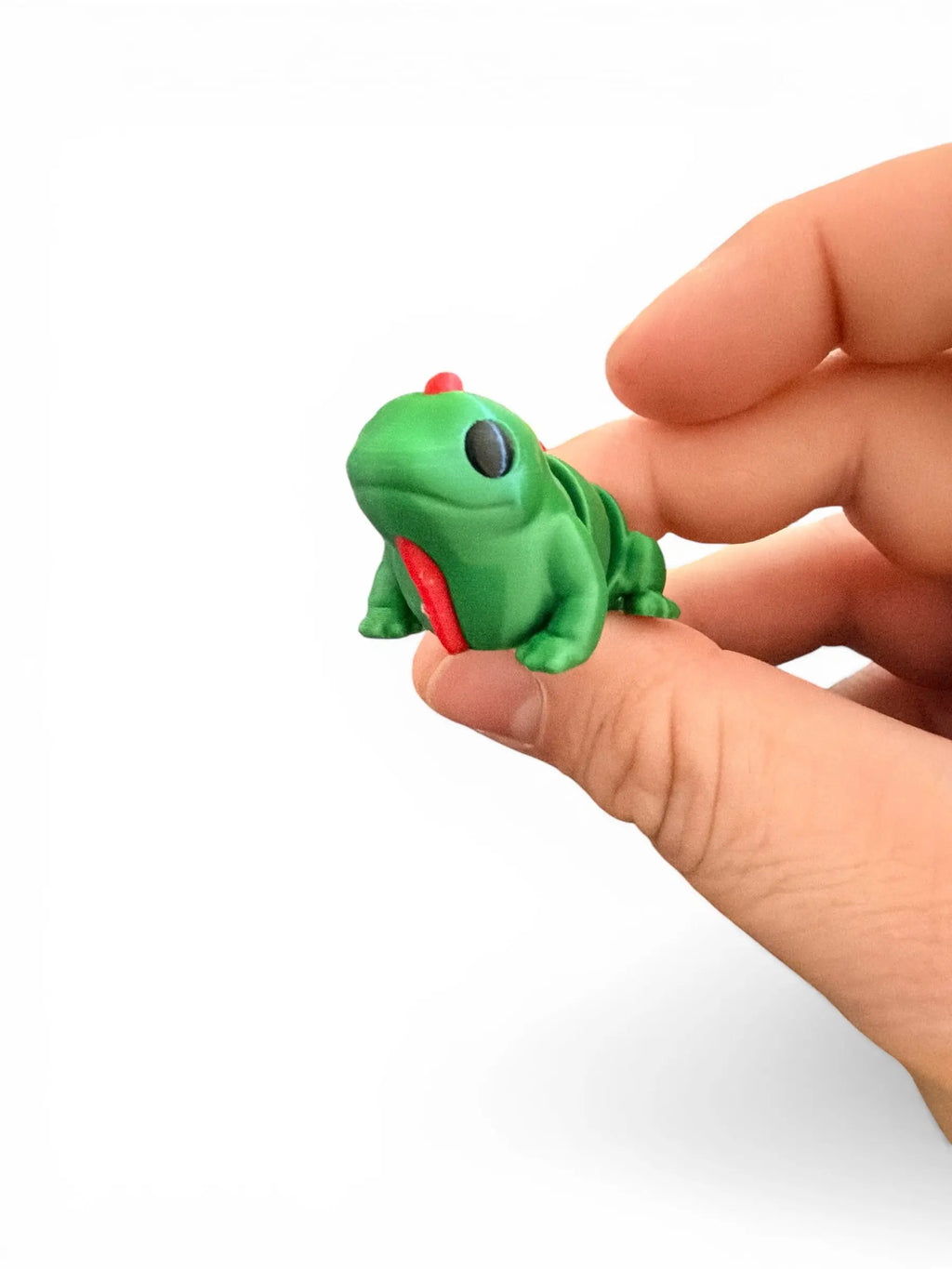 Small green lizard figurine held between fingers against a white background