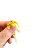 Green flexi gecko held between fingers against a white background