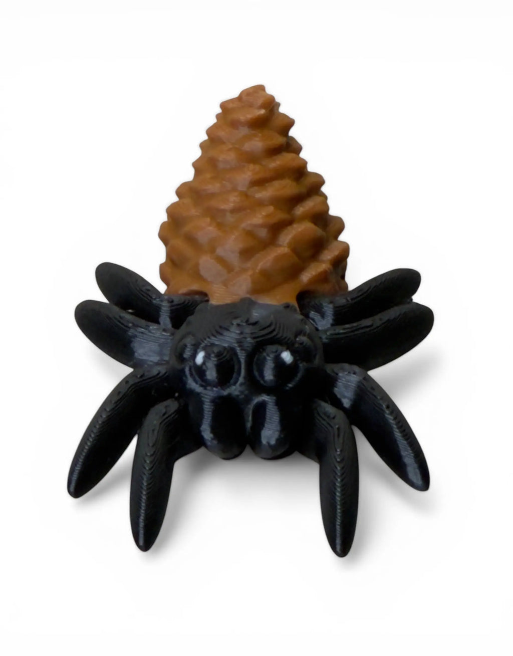 Black spider toy with a brown pine cone on a white background