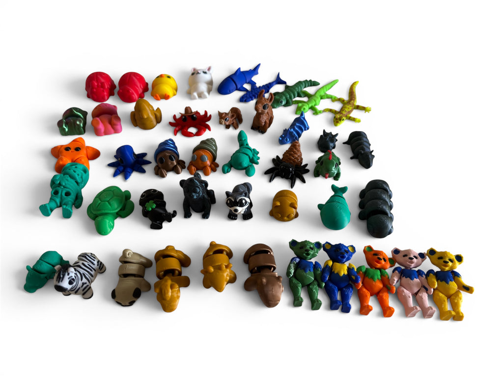 Collection of small animal figurines in various colors on a white background