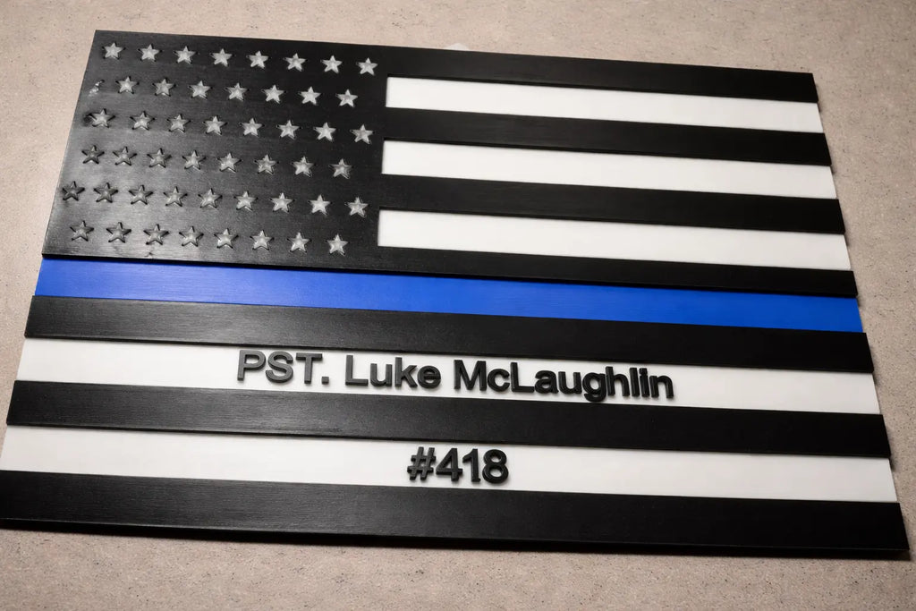 American flag with blue line and text 'PST. Luke McLaughlin #418' on a beige surface